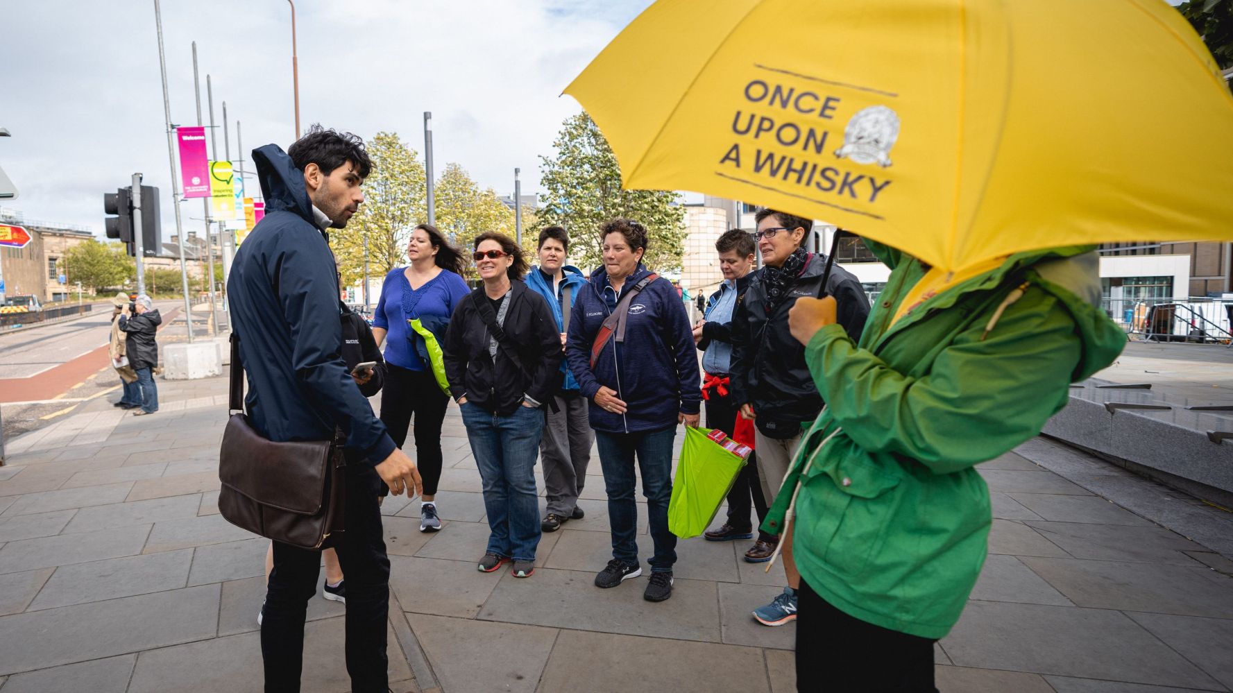 a group of people walking down a sidewalk holding an umbrella