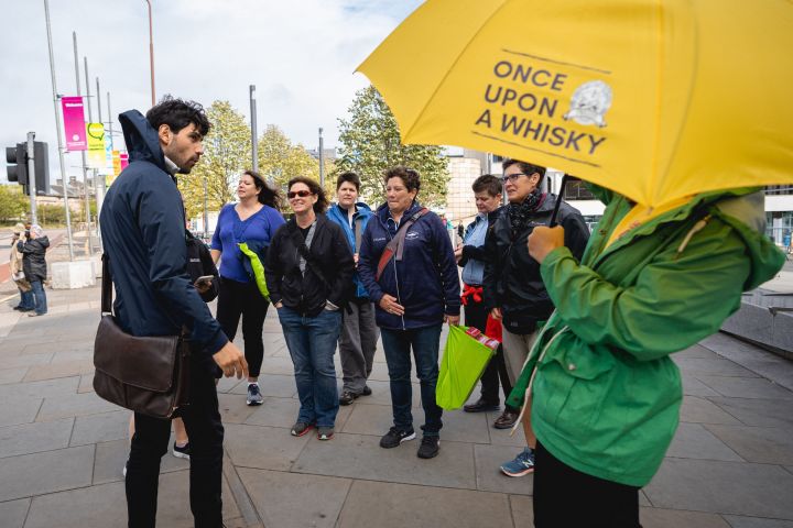 a group of people walking down a sidewalk holding an umbrella