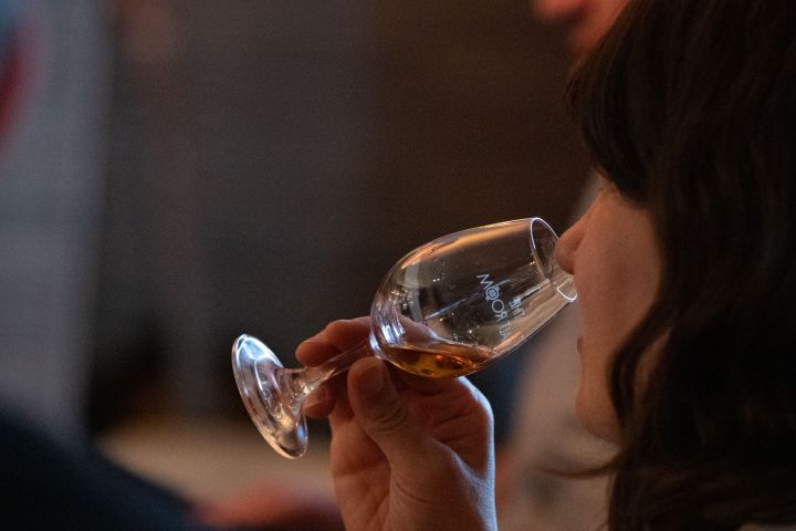 Person smelling a glass of whiskey with focus on the drink.