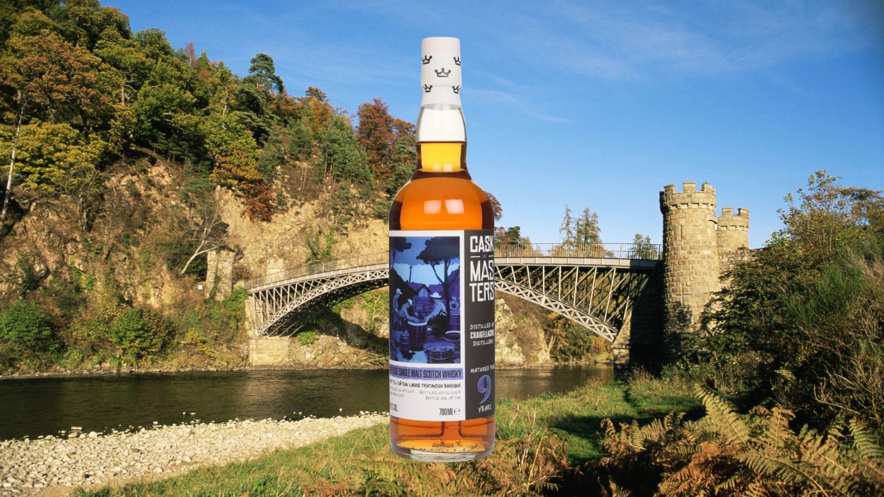 Whisky bottle in front of a river and a historic bridge.