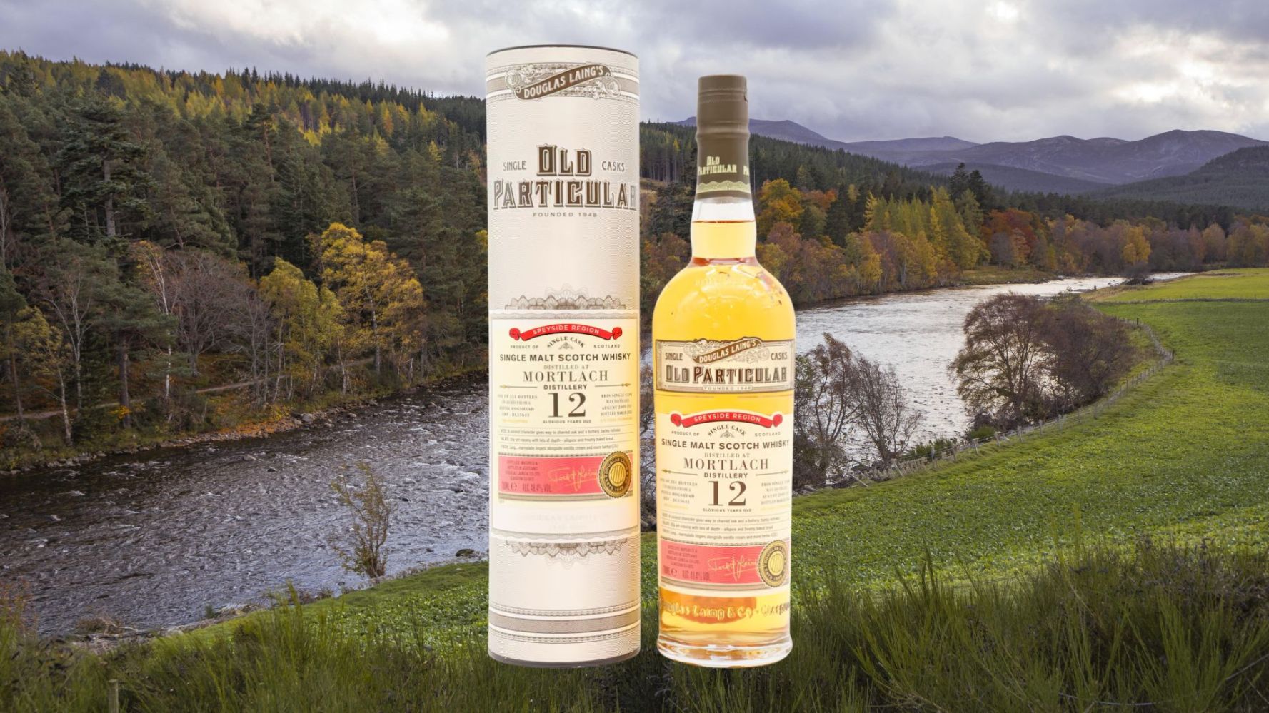 Whisky bottle and box by a river, forest, and mountains.
