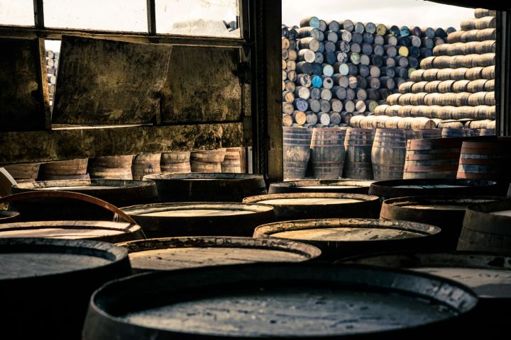 Warehouse with rows of stacked wooden barrels inside and outside.