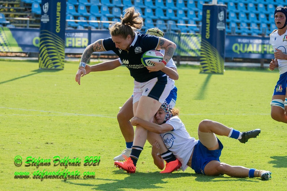 Rugby player tackling opponent during a match on a grassy field.